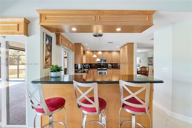 kitchen with a kitchen bar, hanging light fixtures, light tile patterned flooring, stainless steel appliances, and a sink