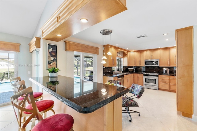 kitchen with decorative backsplash, a kitchen bar, visible vents, and appliances with stainless steel finishes