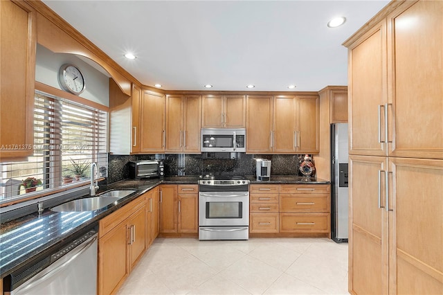 kitchen with dark stone counters, light tile patterned floors, decorative backsplash, stainless steel appliances, and a sink