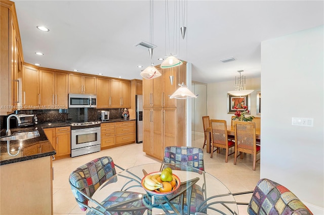 kitchen with visible vents, a sink, stainless steel appliances, light tile patterned floors, and decorative backsplash