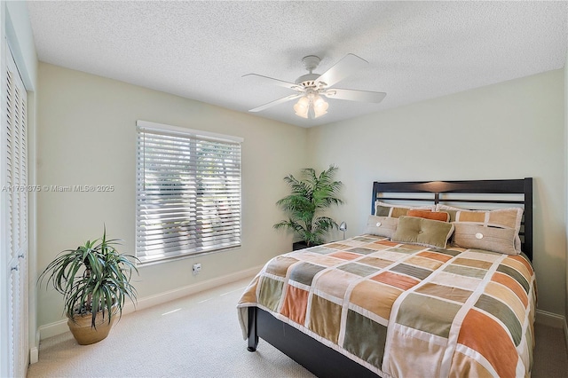 bedroom with ceiling fan, baseboards, carpet floors, and a textured ceiling