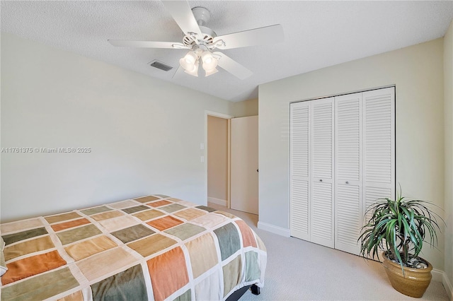 bedroom featuring visible vents, light carpet, a textured ceiling, a closet, and ceiling fan