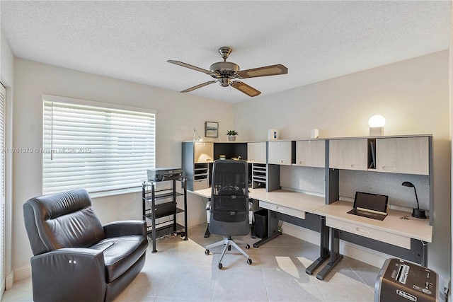 home office with light tile patterned floors, a ceiling fan, baseboards, and a textured ceiling