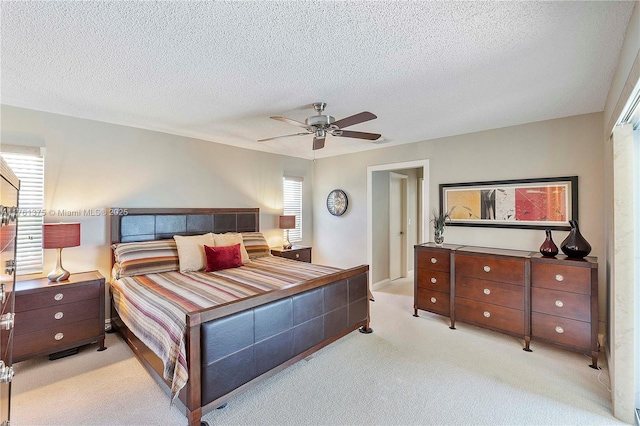 bedroom featuring light colored carpet, a ceiling fan, and a textured ceiling