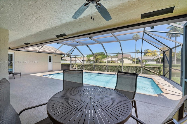 outdoor pool featuring outdoor dining space, glass enclosure, a patio, and a ceiling fan