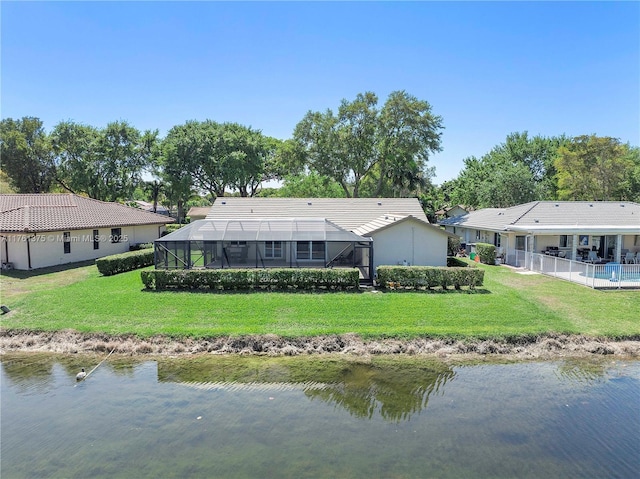 back of property featuring glass enclosure, a tiled roof, a yard, and a water view