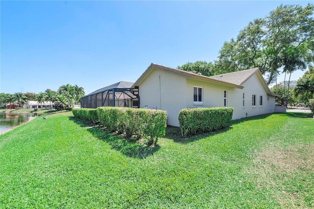 view of home's exterior featuring a lawn, glass enclosure, and stucco siding