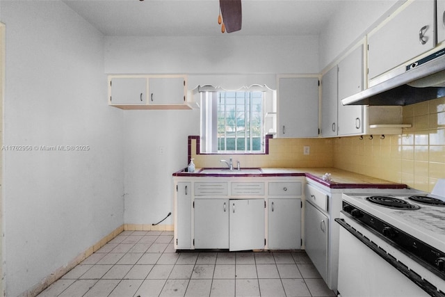 kitchen with backsplash, under cabinet range hood, electric stove, light tile patterned flooring, and a sink