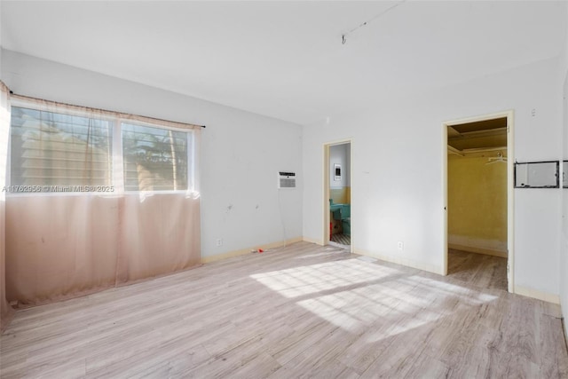 unfurnished bedroom featuring a spacious closet, wood finished floors, and baseboards