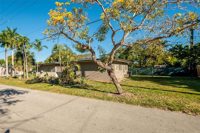 view of side of home with stucco siding, a yard, and fence