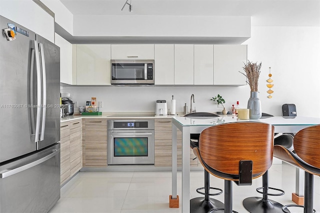 kitchen featuring modern cabinets, a sink, stainless steel appliances, white cabinets, and light countertops