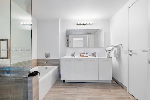 bathroom featuring double vanity, a garden tub, and a sink