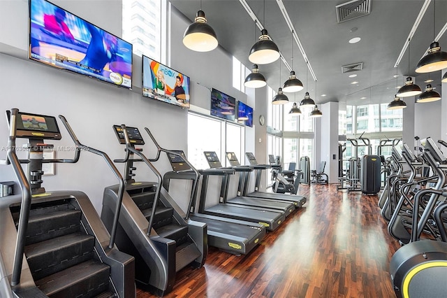 gym featuring visible vents, wood finished floors, and a towering ceiling