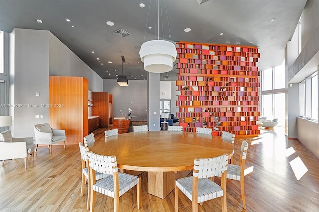 dining space with recessed lighting, visible vents, light wood-style floors, and a high ceiling