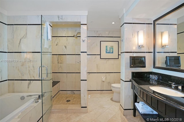 full bathroom featuring toilet, vanity, a stall shower, a bath, and tile walls