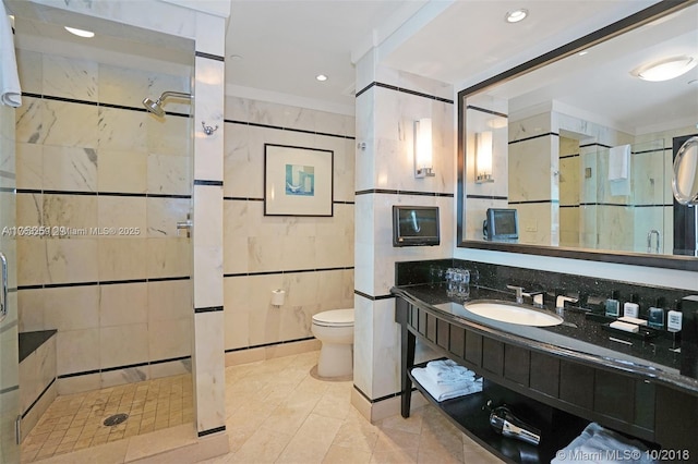 full bath with tile patterned flooring, toilet, vanity, a stall shower, and tile walls