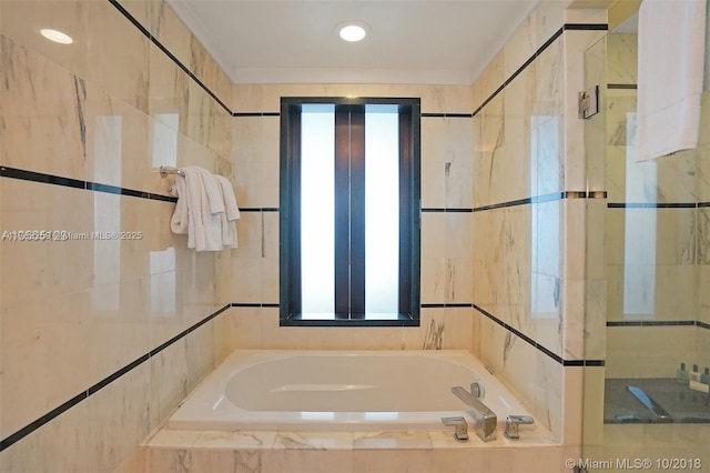 bathroom with a garden tub and tile walls