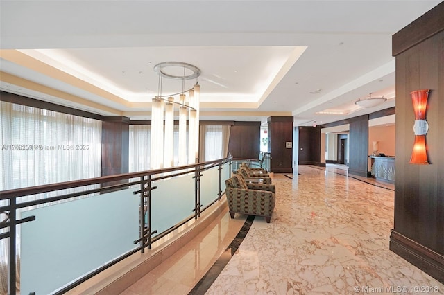 hall featuring marble finish floor and a tray ceiling