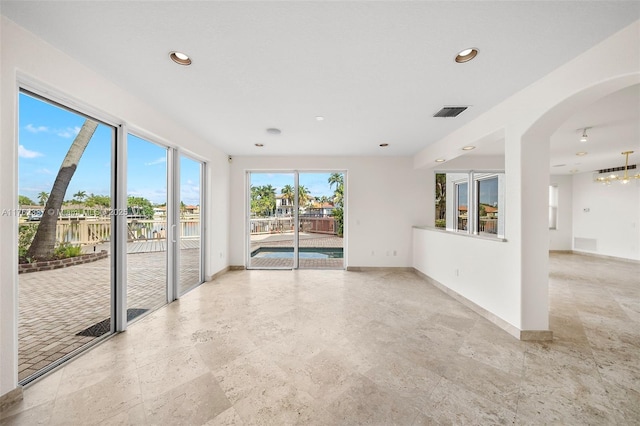 unfurnished room with arched walkways, visible vents, recessed lighting, and baseboards