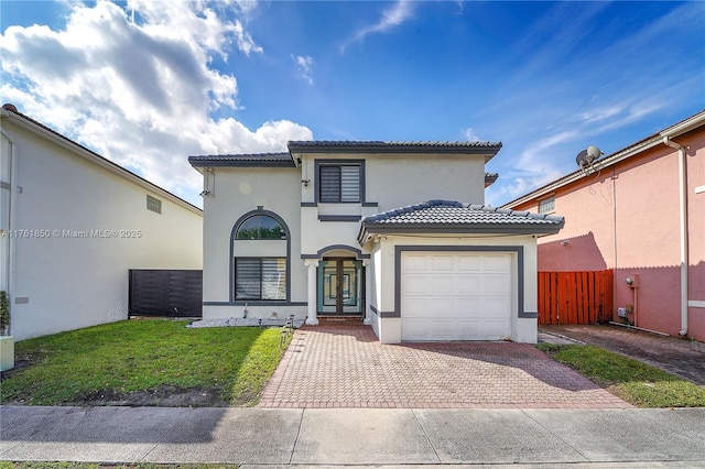 mediterranean / spanish house featuring decorative driveway, stucco siding, an attached garage, and a tile roof