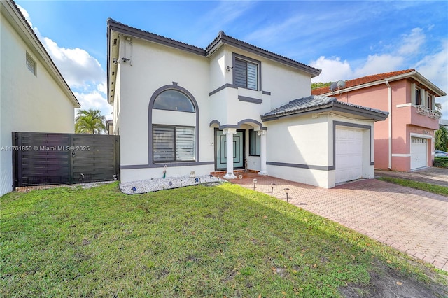 mediterranean / spanish house with an attached garage, stucco siding, a front lawn, a tiled roof, and decorative driveway