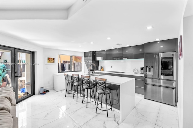 kitchen with a breakfast bar area, a sink, stainless steel refrigerator with ice dispenser, modern cabinets, and marble finish floor