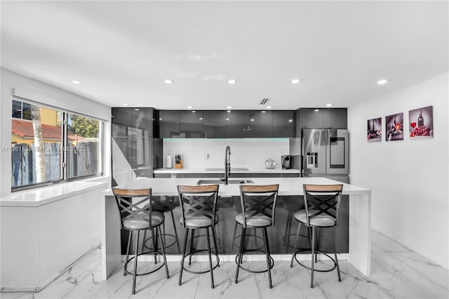 kitchen featuring light countertops, stainless steel fridge with ice dispenser, modern cabinets, and a sink