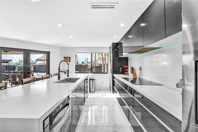 kitchen featuring marble finish floor, modern cabinets, a sink, black electric cooktop, and dark cabinets