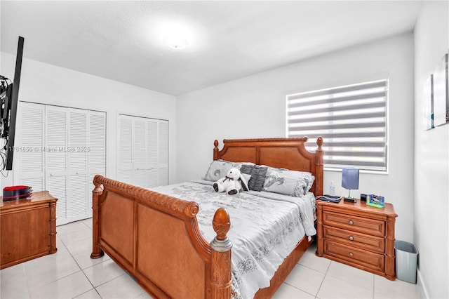 bedroom with light tile patterned flooring and two closets