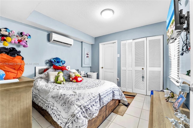 bedroom with a wall mounted air conditioner, a closet, a textured ceiling, and light tile patterned floors