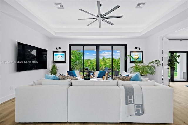 living room featuring visible vents, a tray ceiling, and wood finished floors