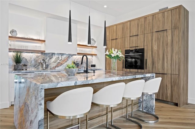 kitchen with light wood finished floors, black oven, modern cabinets, and open shelves