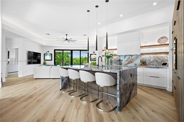 kitchen featuring a kitchen bar, modern cabinets, open shelves, tasteful backsplash, and white cabinets