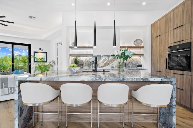 kitchen with a sink, modern cabinets, visible vents, and oven