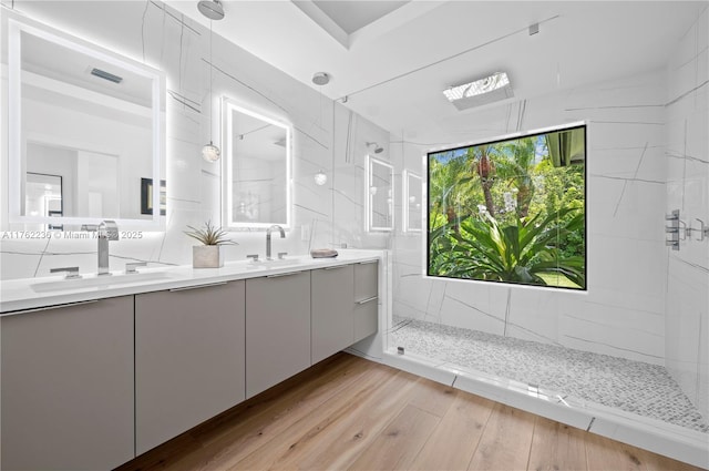 full bath with visible vents, walk in shower, double vanity, wood finished floors, and a sink