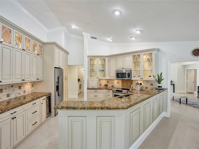 kitchen with dark stone counters, vaulted ceiling, appliances with stainless steel finishes, and a sink