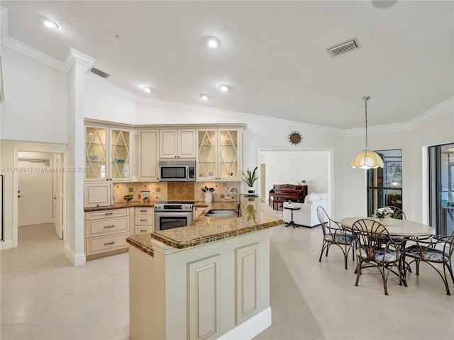 kitchen featuring visible vents, dark stone counters, a sink, stainless steel appliances, and cream cabinets