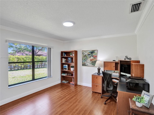 home office featuring baseboards, visible vents, light wood-style flooring, ornamental molding, and a textured ceiling