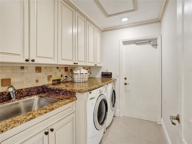 laundry area featuring crown molding, washing machine and dryer, light tile patterned flooring, cabinet space, and a sink