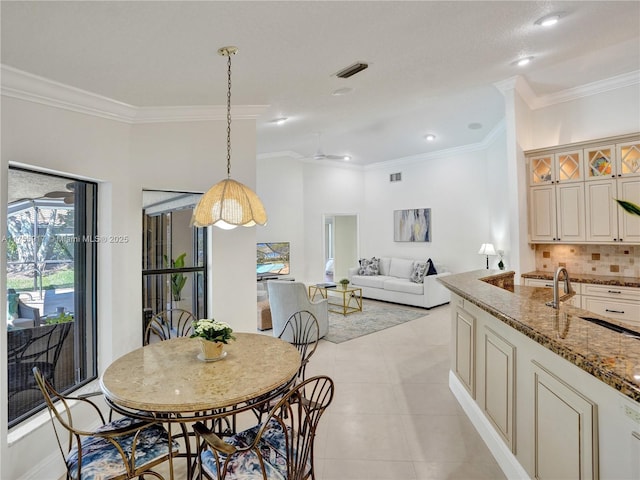 dining area featuring light tile patterned floors, visible vents, crown molding, and ceiling fan