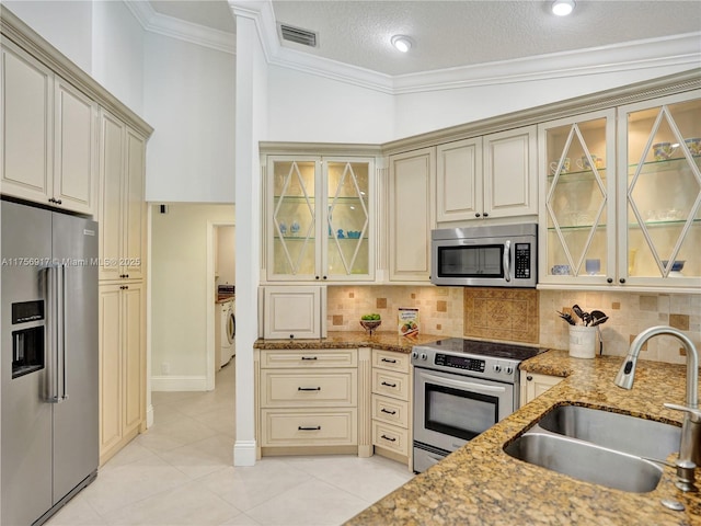 kitchen with visible vents, washer / dryer, a sink, stainless steel appliances, and cream cabinets