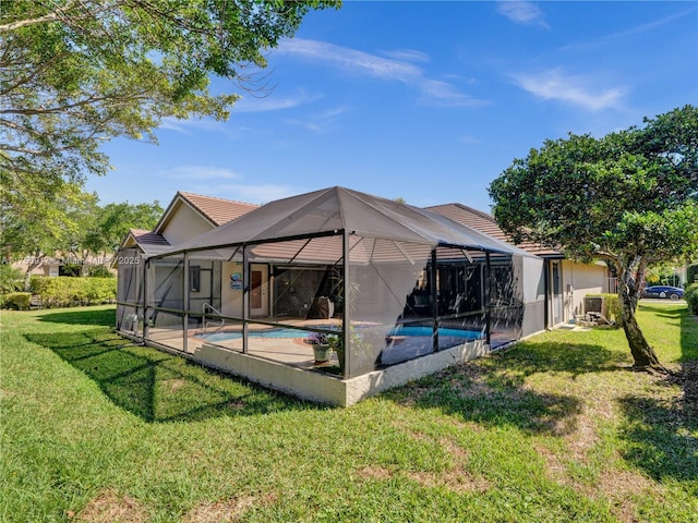 rear view of property featuring a lanai, a tile roof, stucco siding, a yard, and an outdoor pool