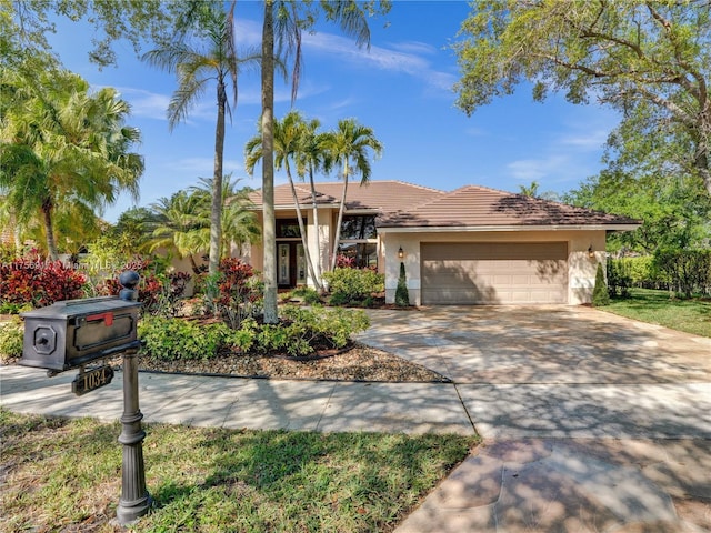 ranch-style house featuring a tile roof, a garage, driveway, and stucco siding