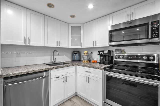 kitchen featuring a sink, decorative backsplash, appliances with stainless steel finishes, and white cabinetry