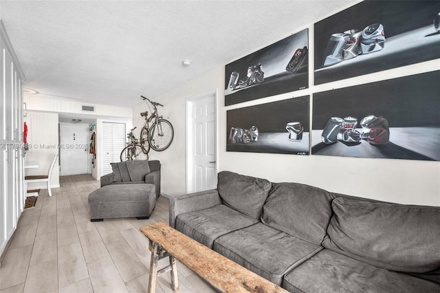 living area featuring wood finished floors, visible vents, and a textured ceiling