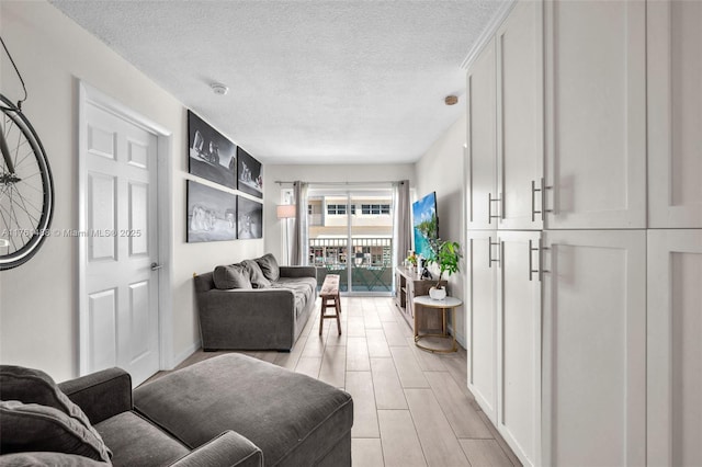 living room with wood tiled floor, baseboards, and a textured ceiling