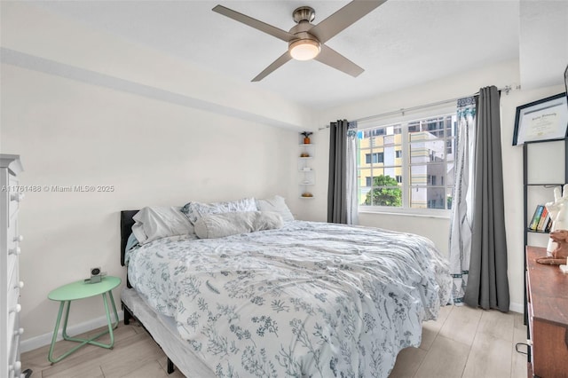 bedroom featuring light wood finished floors, a ceiling fan, and baseboards