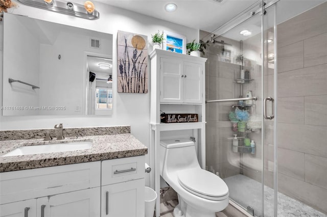 bathroom featuring visible vents, toilet, a stall shower, and vanity