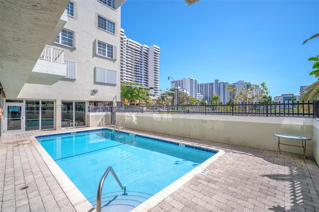 pool with a city view, a patio, and fence