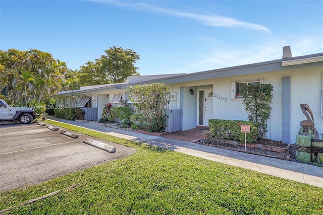 ranch-style house featuring stucco siding, a front yard, and uncovered parking